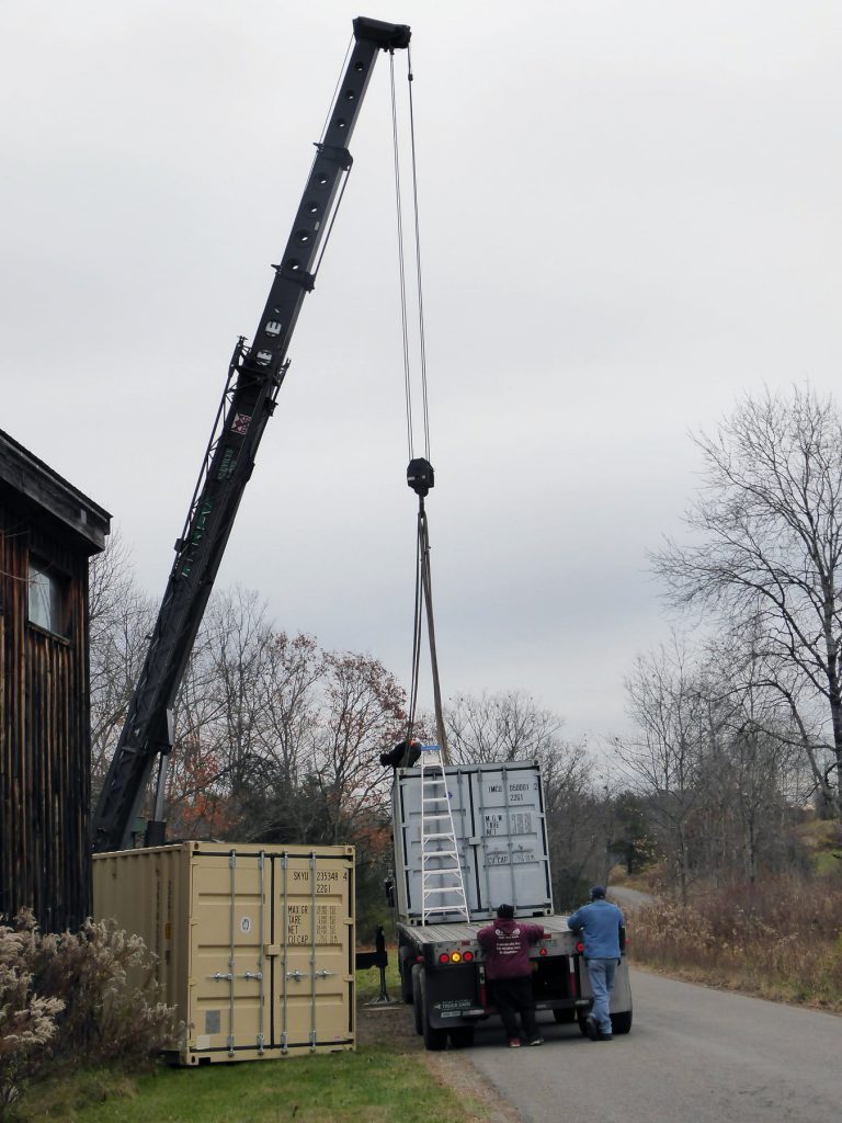 A crane loads a shipping container onto a flatbed truck