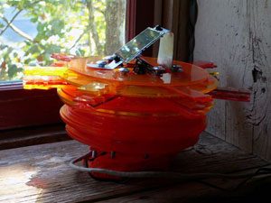 Sunsmile #3, a stack of translucent orange discs by a window